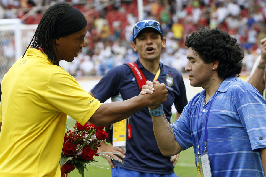 Легенда аргентинского футбола Диего Марадона (справа) приветствует бразильца Роналдиньо в финале мужского футбольного турнира между Нигерией и Аргентиной на Национальном стадионе Олимпиады 2008 года в Пекине, 23 августа 2008 года