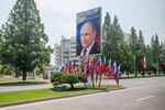 Баннер с портретом президента РФ Владимира Путина и российские флаги на улице в Пхеньяне, 18 июня 2024 года