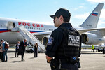 Сотрудник полиции на фоне самолета Ил-96-300 специального летного отряда «Россия», вылетевшего из московского аэропорта «Внуково», в Международном аэропорту Анкоридж имени Теда Стивенса, 14 августа 2025 года