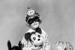Девочка в шляпе клоуна и с маской Микки Мауса на вечеринке в честь Хэллоуина, 1930-е годы