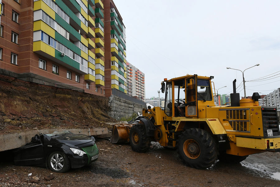 Легковой автомобиль, раздавленный обрушившейся подпорной стеной, возле жилого дома на проспекте 60-летия образования СССР в Красноярске, 6 августа 2021 года