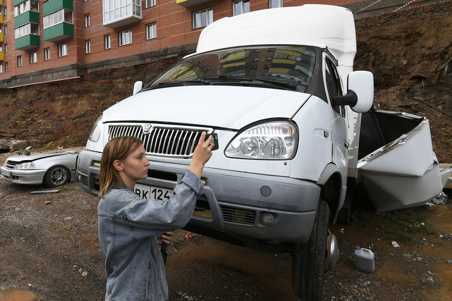 Журналистка снимает место обрушения подпорной стеной возле жилого дома на проспекте 60-летия образования СССР в Красноярске, 6 августа 2021 года