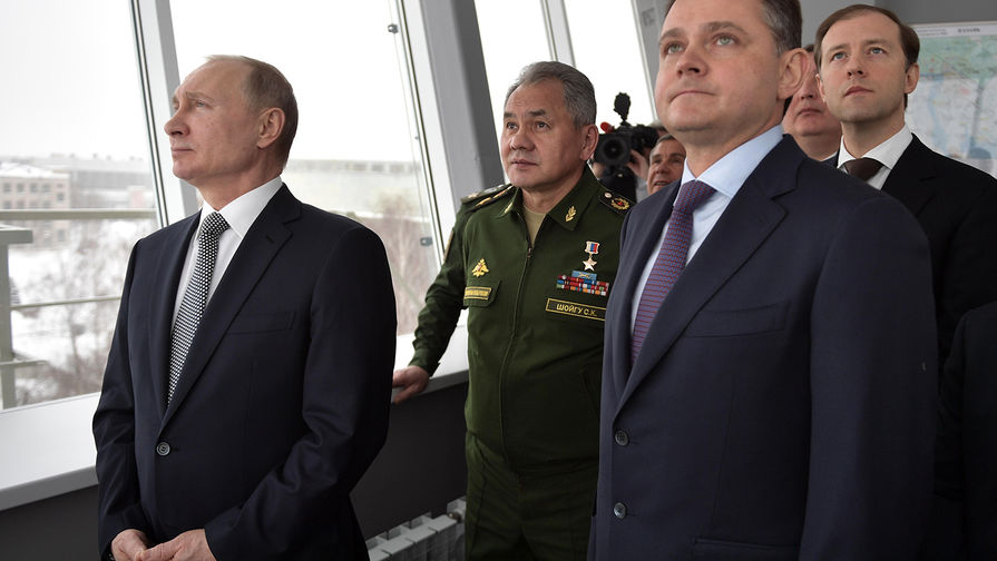 Владимир Путин и министр обороны РФ Сергей Шойгу (второй слева) наблюдают за демонстрационным полетом нового сверхзвукового стратегического бомбардировщика-ракетоносца «Ту-160М» «Петр Дейнекин» во время посещения Казанского авиационного завода имени С. П. Горбунова, 25 января 2018 года