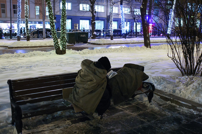 Бездомный житель города читает книгу на скамейке на Страстном бульваре