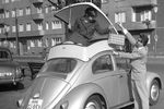 Девушка демонстрирует контейнер, установленный на крыше автомобиля Volkswagen Beetle, который обеспечивает дополнительное место для багажа на Международной выставке пластмасс в Дюссельдорфе, Германия, 1959 год
