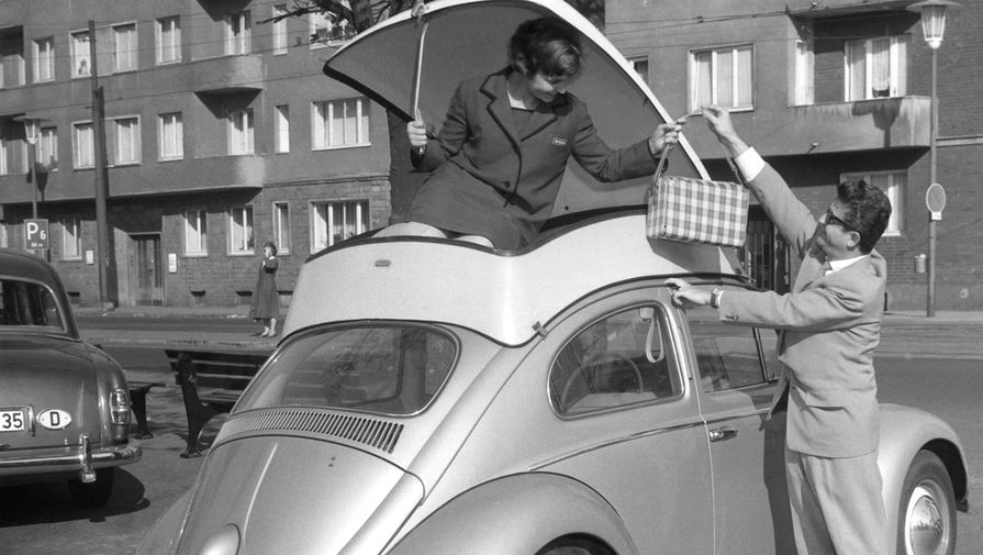 Девушка демонстрирует контейнер, установленный на&nbsp;крыше автомобиля Volkswagen Beetle, который обеспечивает дополнительное место для&nbsp;багажа на&nbsp;Международной выставке пластмасс в&nbsp;Дюссельдорфе, Германия, 1959&nbsp;год