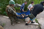 Боец народного ополчения и местные жители эвакуируют ополченца, раненного во время боя с украинскими погранвойсками в микрорайоне Мирный на окраине Луганска