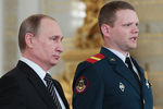 Владимир Путин и командир отделения реактивной артиллерийской батареи 810-й отдельной бригады морской пехоты Черноморского флота младший сержант Олег Баранов (слева направо), награжденный знаком отличия «Георгиевский Крест» IV степени, в Кремле на церемонии вручения государственных наград военнослужащим и специалистам военно-промышленного комплекса, отличившимся в ходе выполнения специальных задач в Сирии