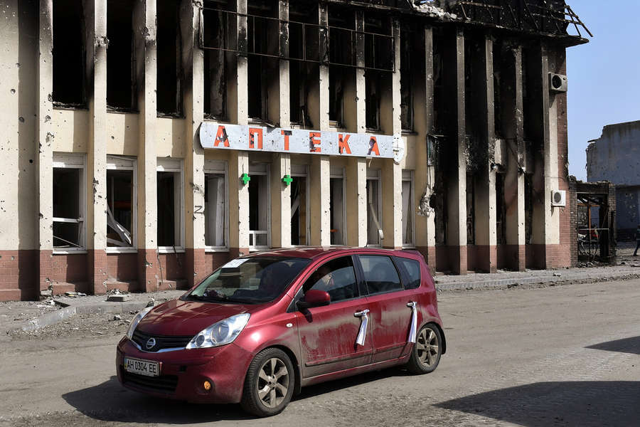 Сгоревшее здание на&nbsp;одной из&nbsp;улиц Волновахи. На&nbsp;первом плане&nbsp;- автомобиль с&nbsp;белыми лентами на&nbsp;дверях, обозначающими, что в&nbsp;машине едут мирные жители, март 2022&nbsp;года