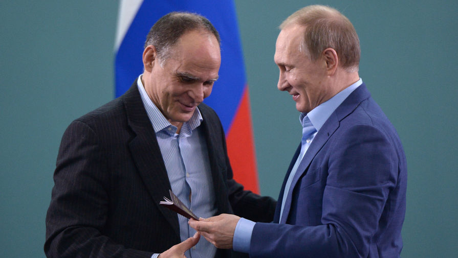 Президент России Владимир Путин (справа) вручает паспорт гражданина РФ тренеру сборной команды России по дзюдо Эцио Гамбе.