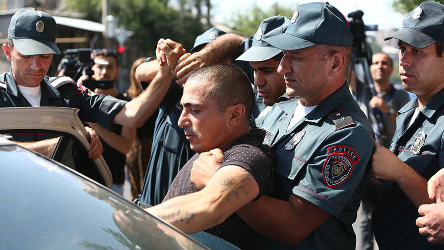 Полицейские сажают в машину задержанного у захваченного здания отделения полиции
