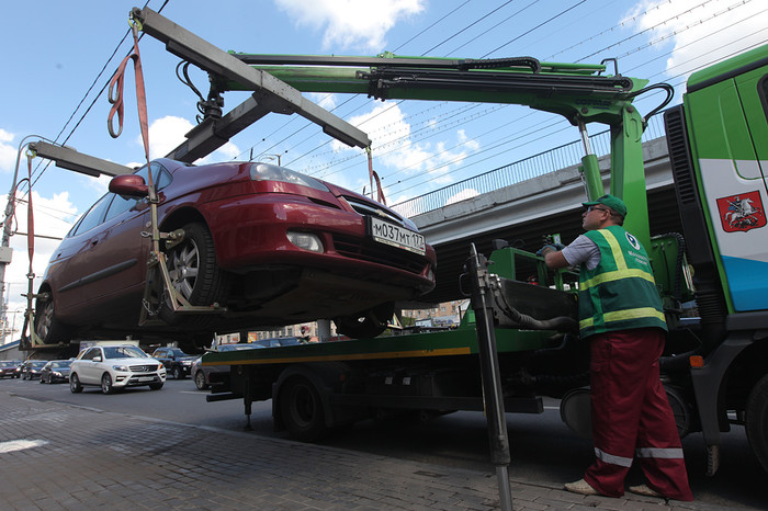 Сотрудник АМПП погружает автомобиль на эвакуатор
