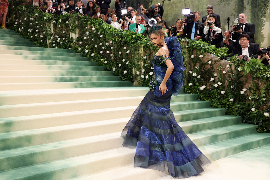 Актриса Зендея выбрала для&nbsp;Met Gala два образа &mdash; и оба были созданы модельером Джоном Гальяно. На&nbsp;красной дорожке она появилась практически в&nbsp;образе ундины &mdash; с&nbsp;фантазийным макияжем и в&nbsp;платье из&nbsp;парчи и органзы в&nbsp;изумрудных, синих, бирюзовых оттенках с&nbsp;отливающими металликом деталями Maison Margiela Artisanal. Второй наряд &mdash; платье со шлейфом и гигантский букет на&nbsp;голове &mdash; стал отсылкой к&nbsp;образу из&nbsp;коллекции Гальяно для&nbsp;Givenchy 1996&nbsp;года.