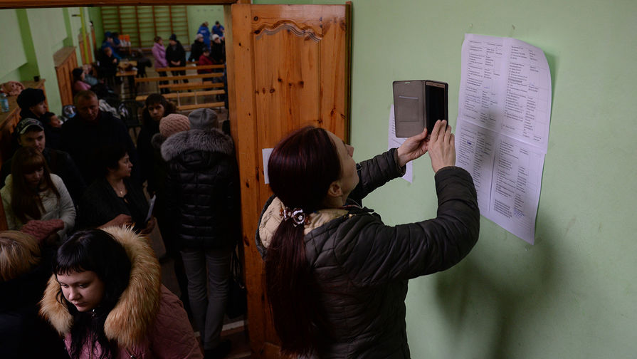 Женщина фотографирует списки пропавших без вести при пожаре, 26 марта 2018 года