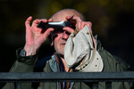 Мужчина наблюдает через фотопленку частичное солнечное затмение в Москве, 25 октября 2022 года