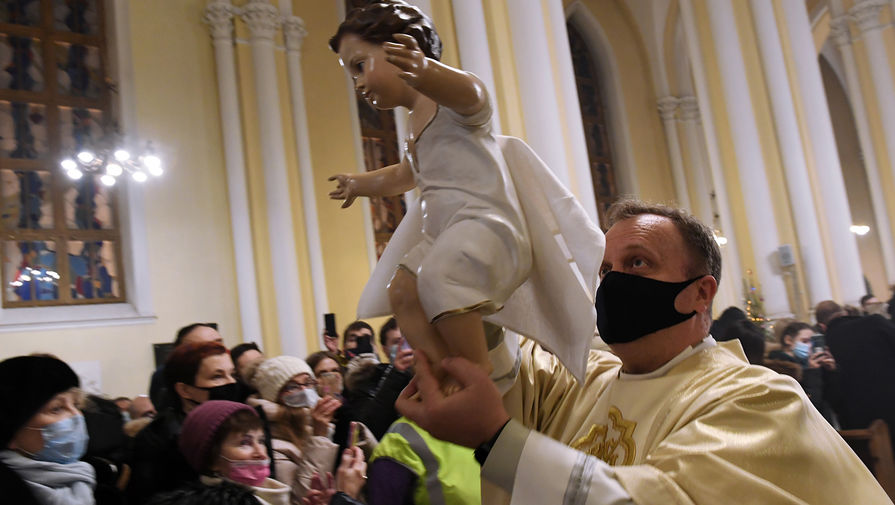 Настоятель римско-католического кафедрального собора Непорочного Зачатия Пресвятой Девы Марии Владимир Кабак во время Рождественской мессы несет фигурку младенца Христа, чтобы уложить ее в&nbsp;рождественские ясли, 24 декабря 2020 года