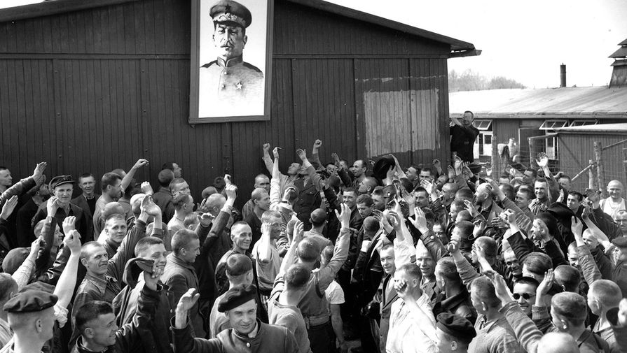 Русские военнопленные, освобожденные армией США, приветствуют портрет Иосифа Сталина в нацистском лагере для военнопленных Бухенвальд, апрель 1945 года