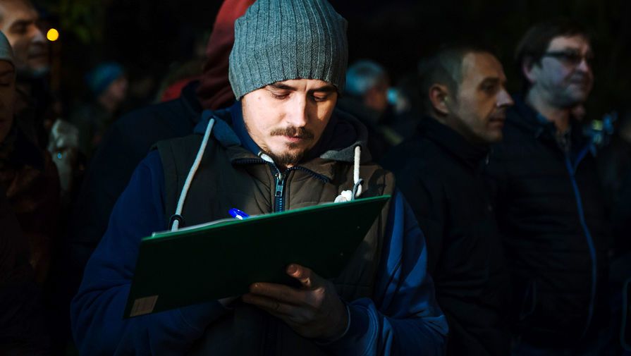 Участник митинга подписывает петицию против платной парковки