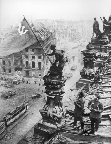 Бойцы 8-й гвардейской армии РККА Алексей Ковалев, Абдулхаким Исмаилов и Леонид Горичев (слева направо) с красным знаменем на крыше здания Рейхстага после взятия города советскими войсками, 2 мая 1945 года