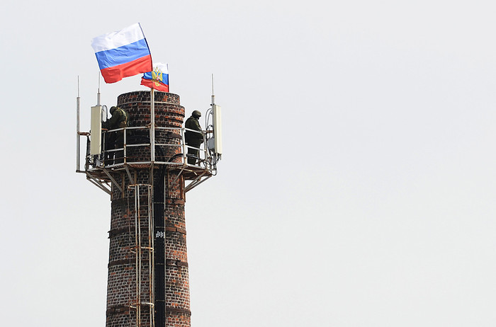 Военнослужащие охраняют российские флаги, водруженные на трубу котельной комплекса зданий штаба ВМС Украины